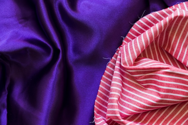 Free photo elevated view of stripes pattern textile and silky purple cloth