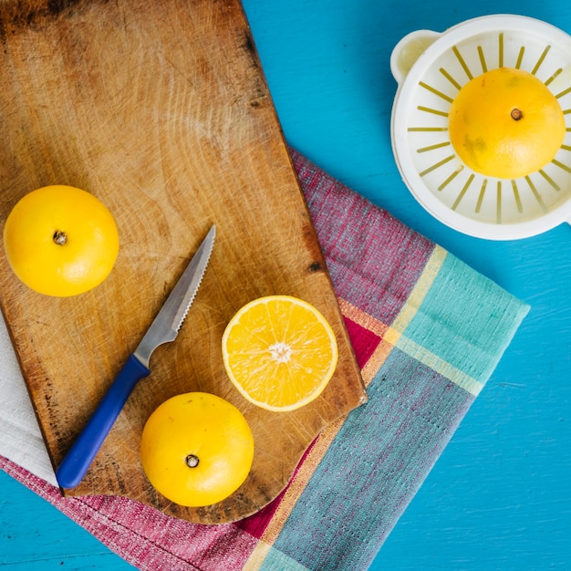 Free photo elevated view of sweet limes and manual juicer on blue backdrop