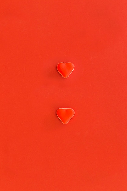 Elevated view of two heart shape candies on red background