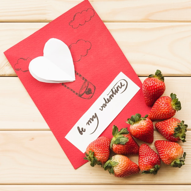 Free photo elevated view of valentine day card with strawberries on wooden background