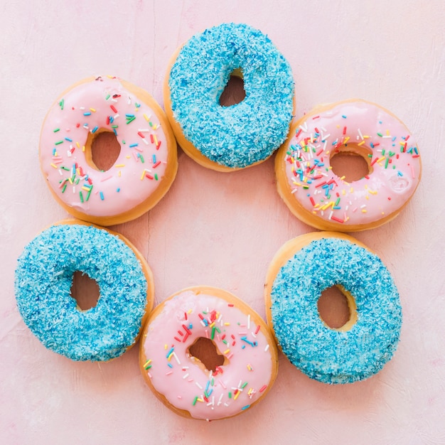 Elevated view of various delicious donuts on pink backdrop