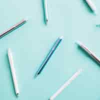 Free photo elevated view of various pens on turquoise colored background