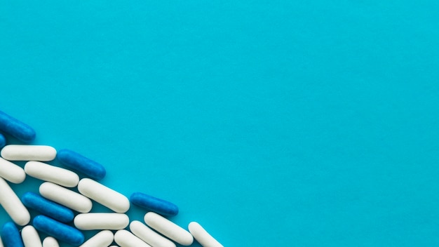 Free photo elevated view of white and blue candy capsules at the corner of cyan backdrop