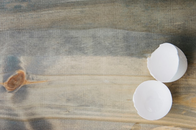 Free photo elevated view of white broken egg shell on wooden background