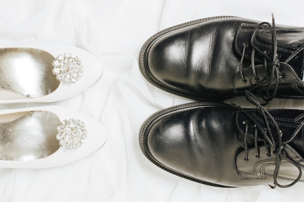 Free photo an elevated view of white high heels and black shoes on scarf