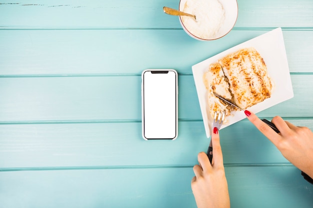 Free photo elevated view of woman's hand cutting lasagne