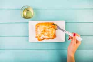 Free photo elevated view of woman's hand eating lasagne on plate