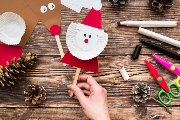 Free Photo an elevated view of woman's hand holding santa claus prop over the table