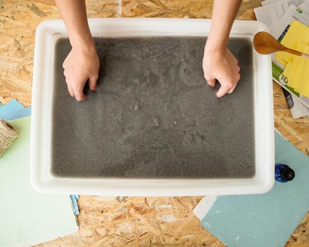 Free photo elevated view of a woman's hand inserting mold in paper pulp