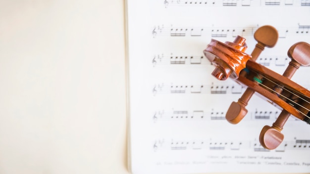 Elevated view of wooden violin scroll and strings on musical notes