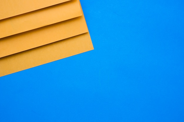 Elevated view of yellow cardboard papers on blue background