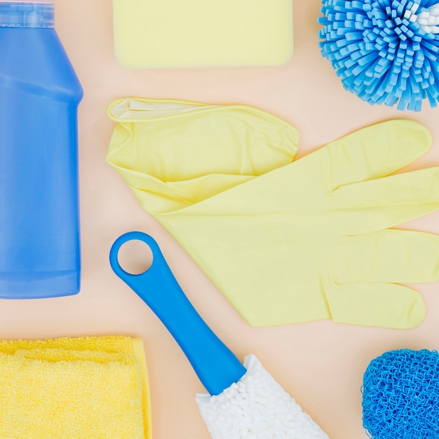 Free photo an elevated view of yellow gloves; sponge; bottle; napkin on peach backdrop