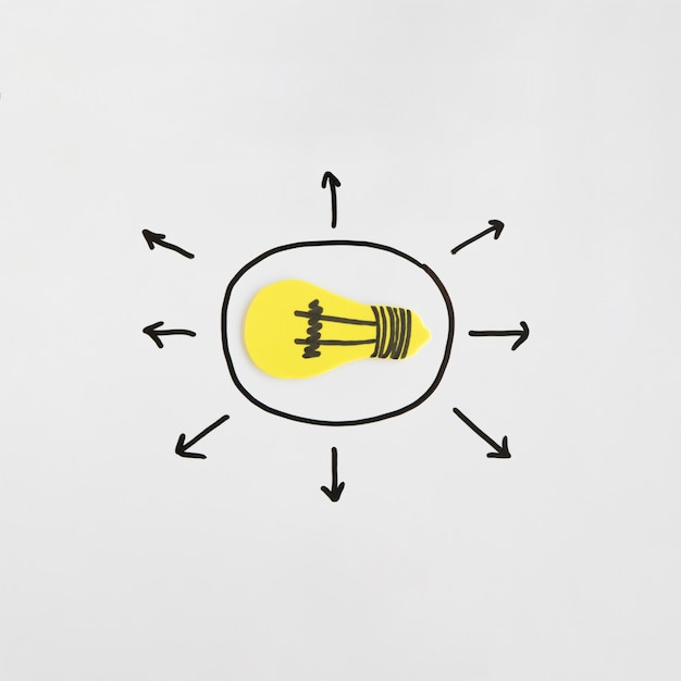 Free Photo elevated view of yellow light bulb surrounded by arrow directional signs on white backdrop