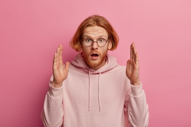 Embarrassed shocked ginger man shows big size gesture