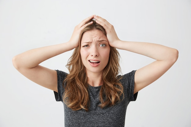 Embarrassed young pretty girl holding her head .