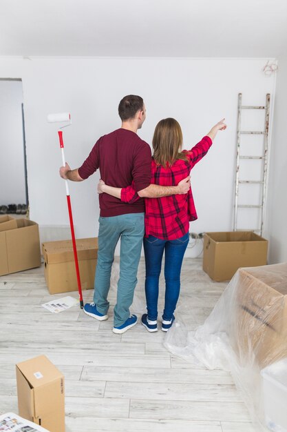 Embracing couple pointing at wall