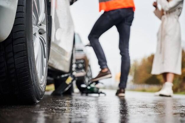 Emergency auto mechanic repairing woman vehicle on the street