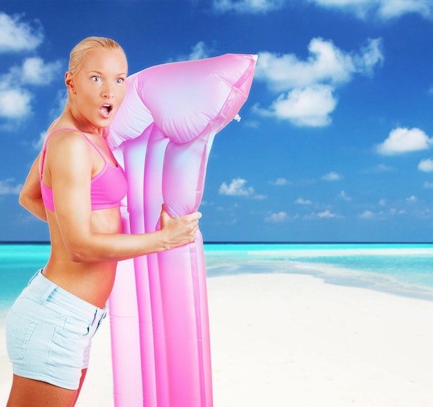 Free photo emotional blond woman posing with pink water matress on white background