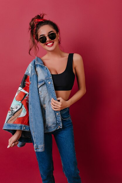 Emotional brunette girl with cute smile posing with new denim jacket