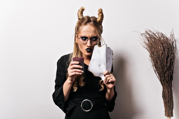 Emotional caucasian woman chilling at halloween party. Good-looking girl in vampire costume preparing for carnival.