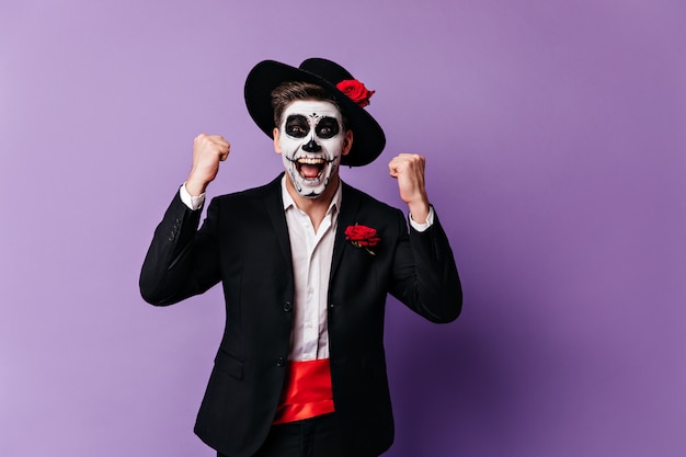 Emotional guy in unusual Mexican outfit at masquerade shouts joyfully, rejoicing in victory.