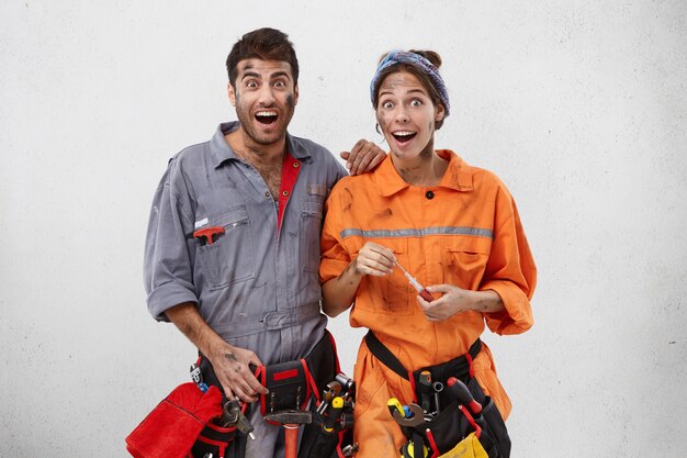 Emotional happy female and male carpenters look with excitement or surprisment