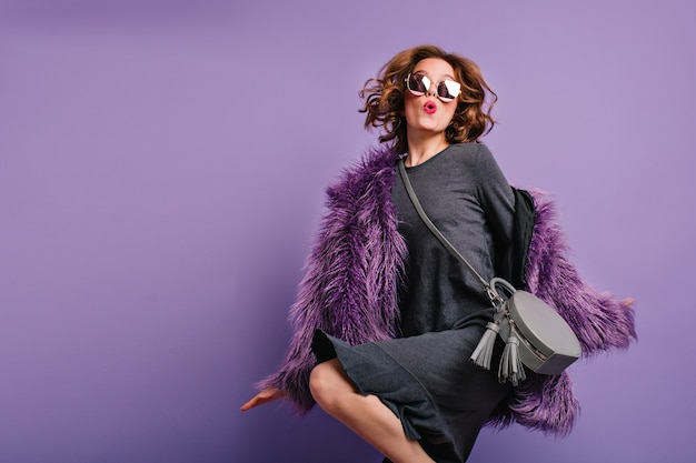 Free photo emotional lady with short curle hair funny dancing in sunglasses and fur coat