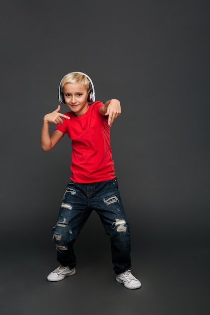 Free Photo emotional little boy child listening music with headphones dancing.