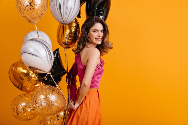 Emotional woman holding bunch of party balloons