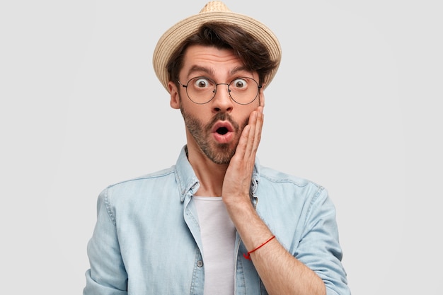 Emotive shocked successful male farmer dressed in casual shirt and straw hat