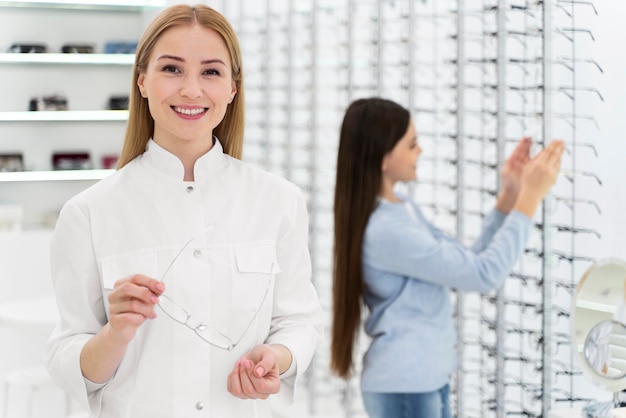 Employee helping girl to try on glasses