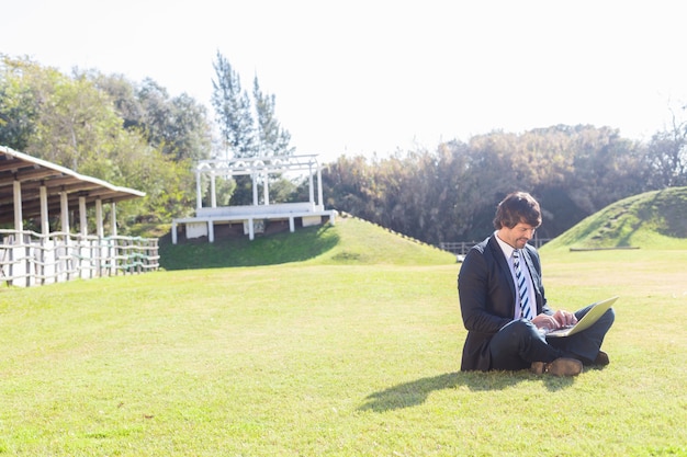 Free photo employee working with his laptop sitting on the grass