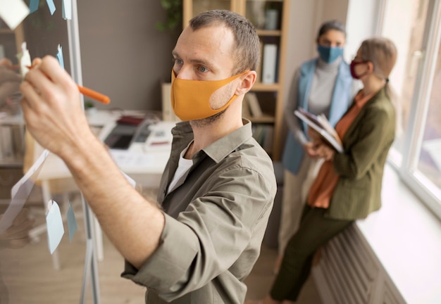 Free Photo employees wearing face masks at the office