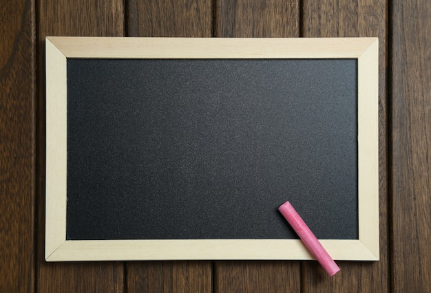 empty blackboard with chalks on vintage wooden background