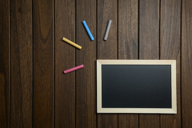 Free photo empty blackboard with chalks on vintage wooden background