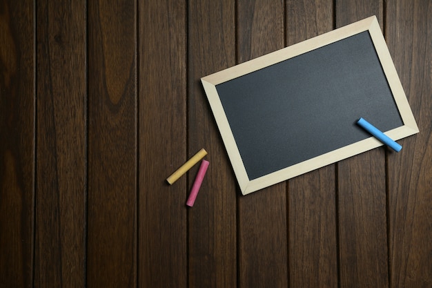 empty blackboard with chalks on vintage wooden background