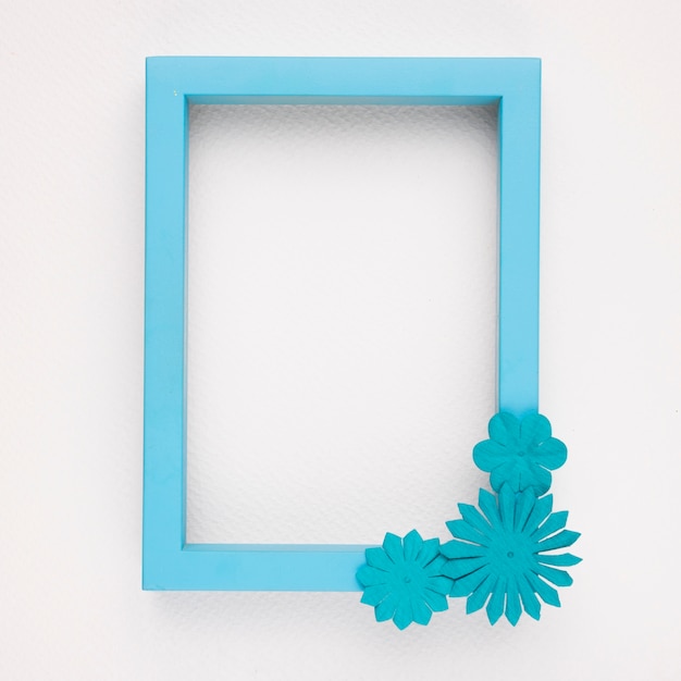 Free Photo an empty blue border frame with flowers on white backdrop