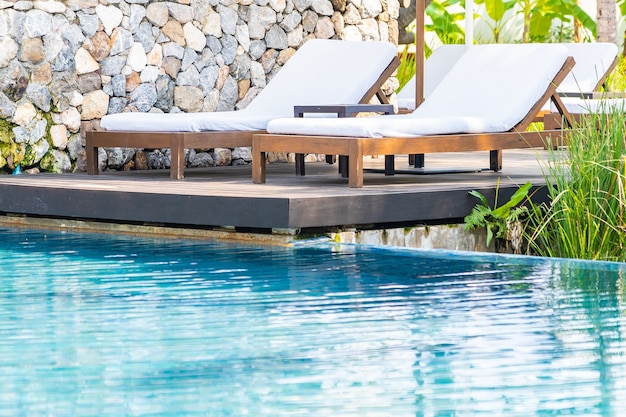 Empty deck chair around outdoor swimming pool in hotel resort for leisure vacation