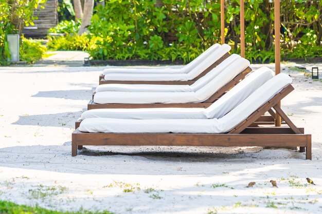 Empty deck chair around outdoor swimming pool in hotel resort for leisure vacation