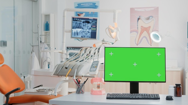 Free photo empty dental cabinet with horizontal green screen on monitor. nobody in dentist office for dentistry care with isolated background and mockup template on computer. stomatological tools