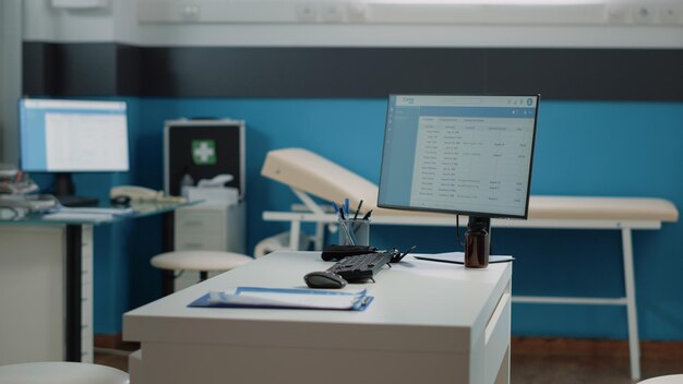 Empty doctors office with medical equipment for healthcare. Nobody in cabinet with tools, instruments, computer and checkup documents on desk. Workplace for doctor at facility.