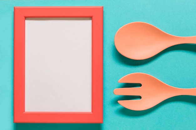 Free photo empty frame with spoon and fork on blue background