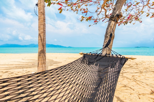 Free photo empty hammock swing around beach sea ocean with white cloud blue sky for travel vacation