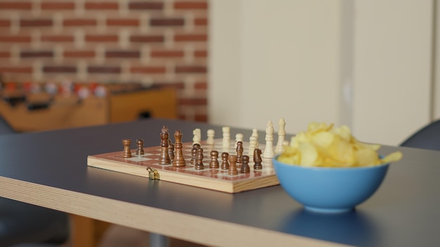 Free photo empty living room table with chess board game and bowl of chips, no people in apartment used to meet and have fun with strategic activity. nobody in space with checkmate play. close up.