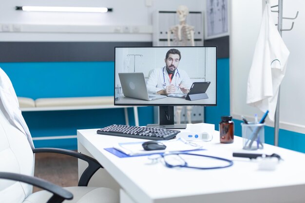 Empty medical office with remote doctor having online discussion during telemedicine videocall meeting conference. Computer with telework videoconference call on screen. Medicine services support