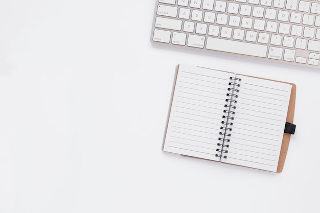 Empty notebook next to keyboard with copy space