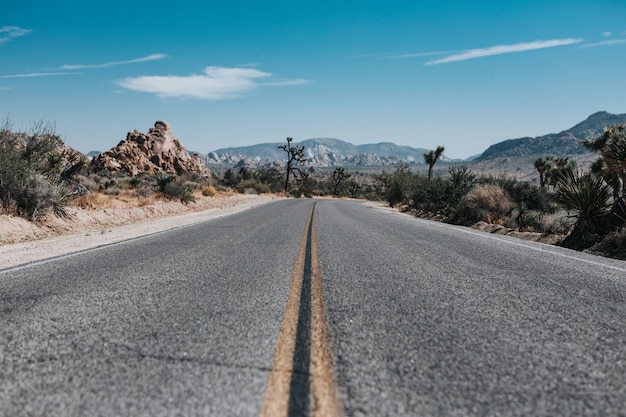 Empty road with mountains in the distance under a blue sky