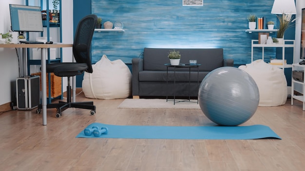 Empty space with training equipment to workout at home. Nobody in living room with floor mat, dumbbells and toning ball to do physical exercise and practice sport. Fitness and gymnastics