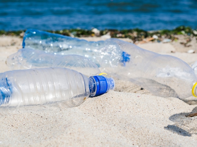 Empty waste water bottle on sand at beach