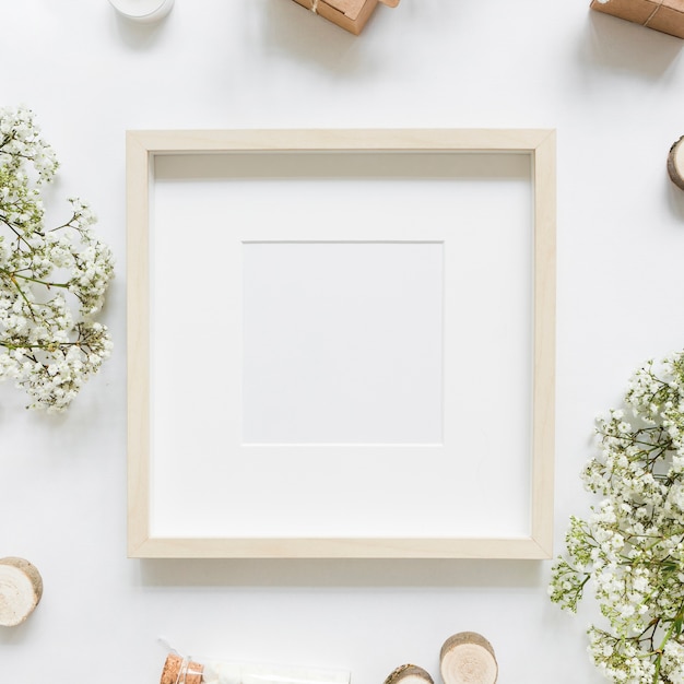 Free photo an empty white frame surrounded with flowers and gift boxes